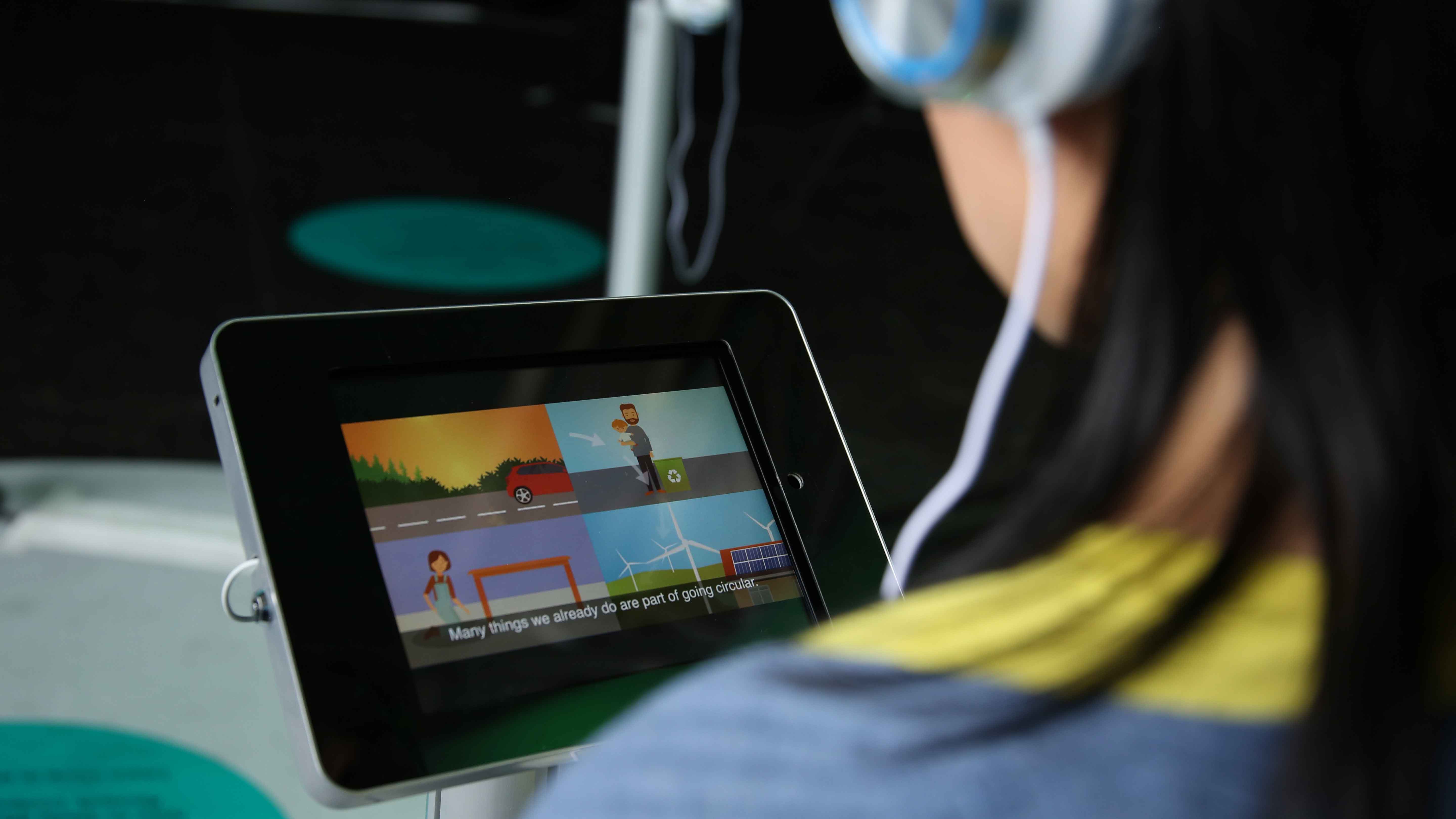 Photo of the back of the head of a woman looking into an ipad screen