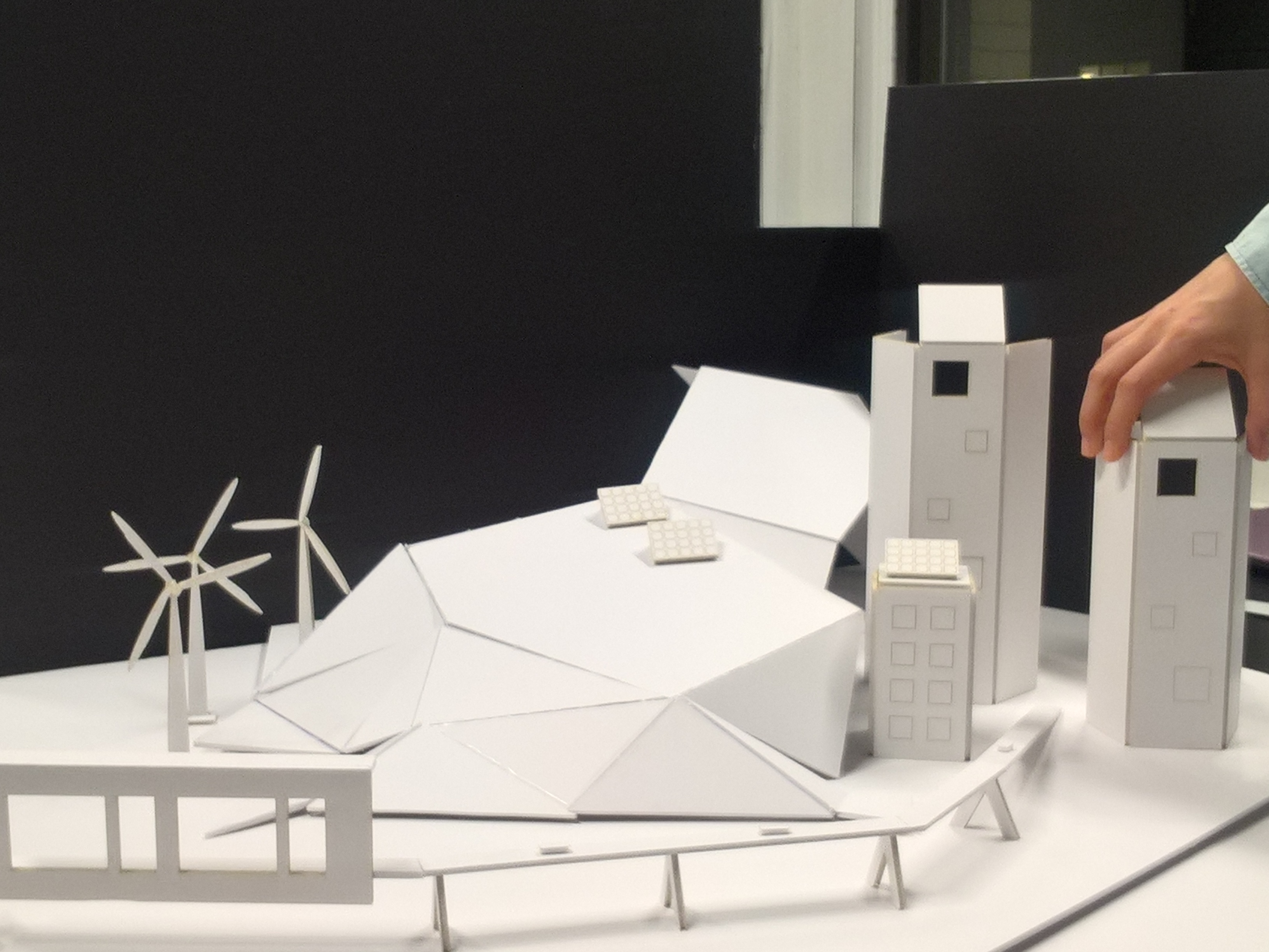 white paper model of a city with solar panels and wind mills