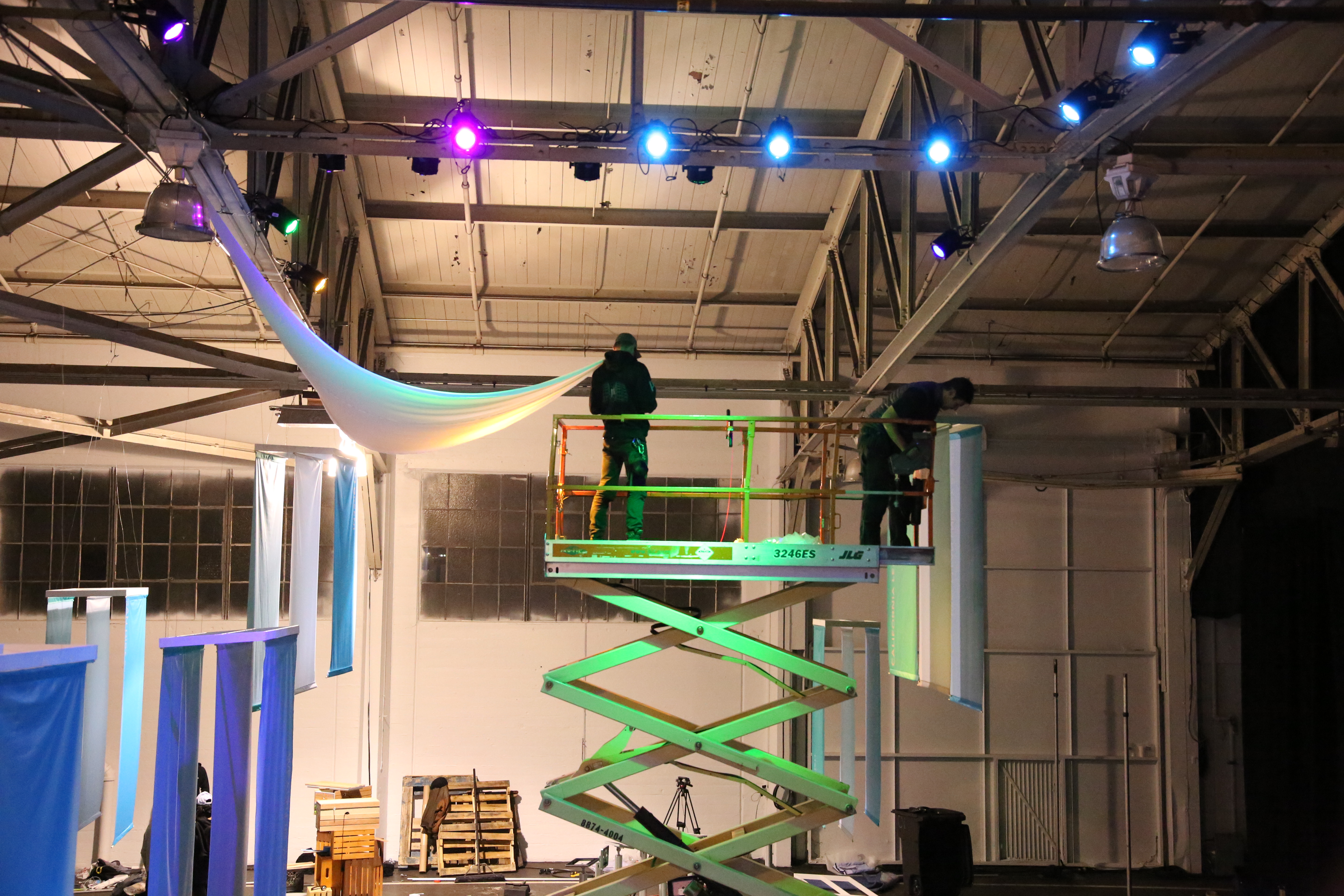 Photo of two men hanging a large cloth from a high celling