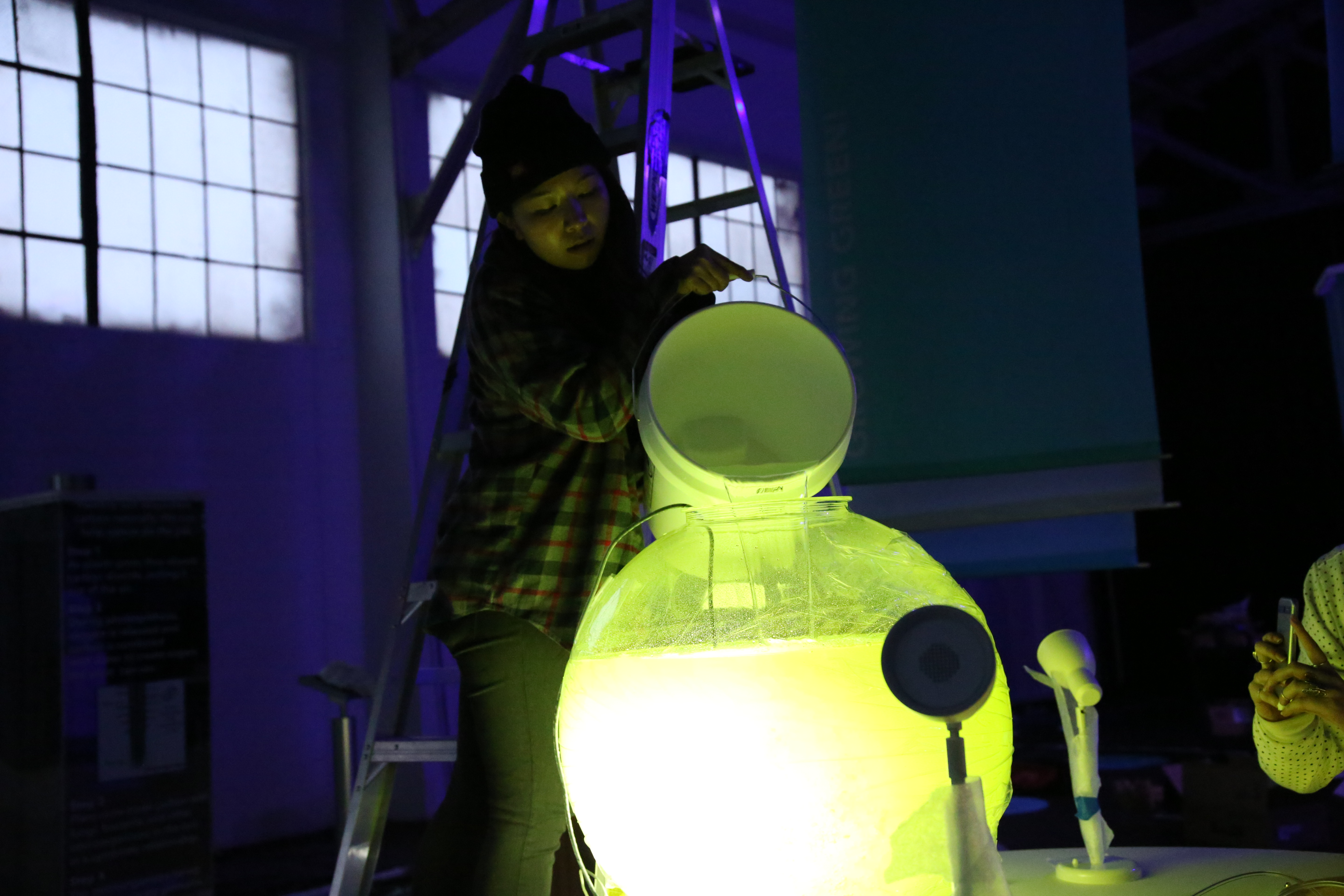 Photo of a woman pouring green liquid into a large translucent sphere
