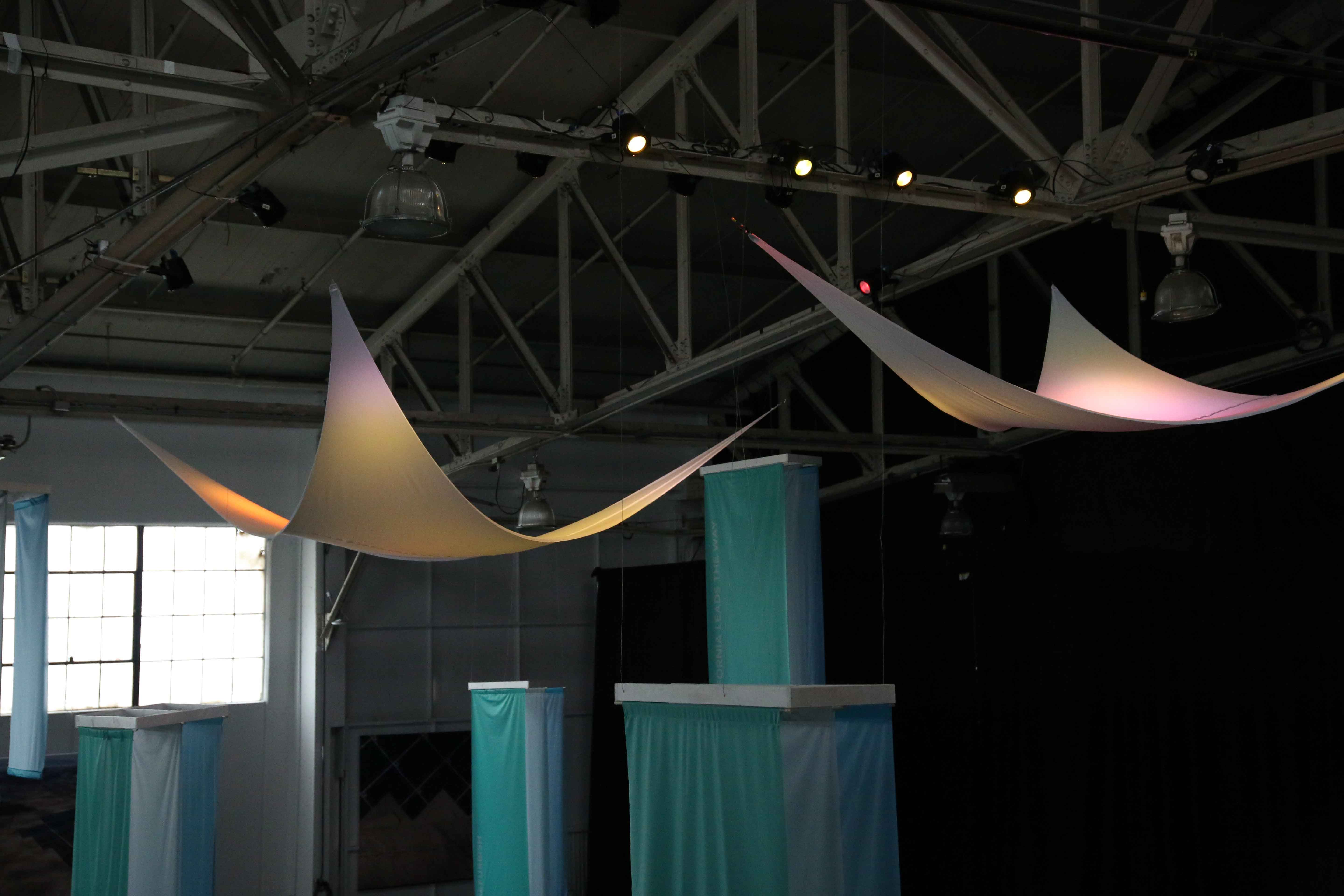 Large, triangular piece of hanging fabric lit up by DMX lights
